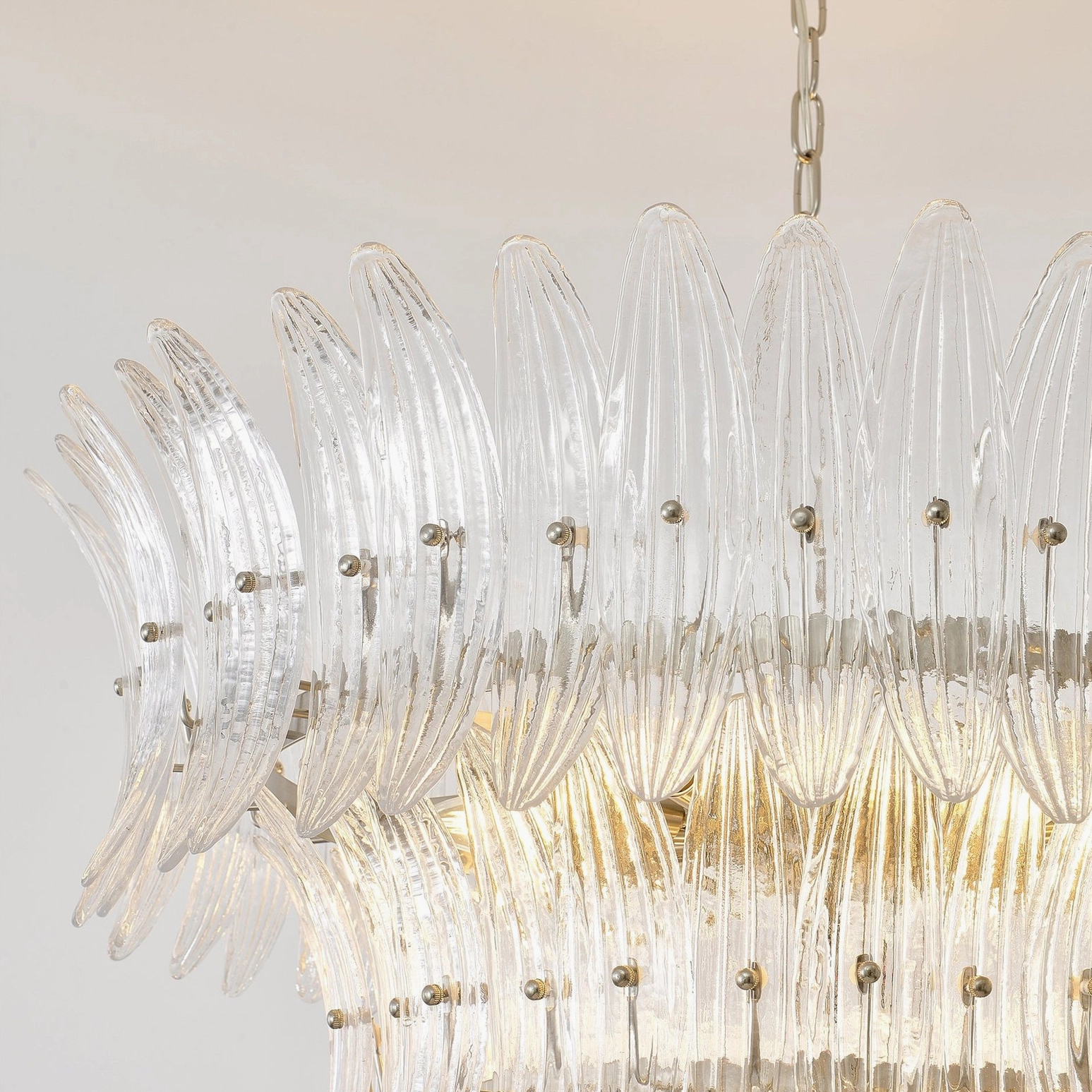 Close-up detail of ribbed palm-shaped glass layers and polished silver metal hardware on chandelier