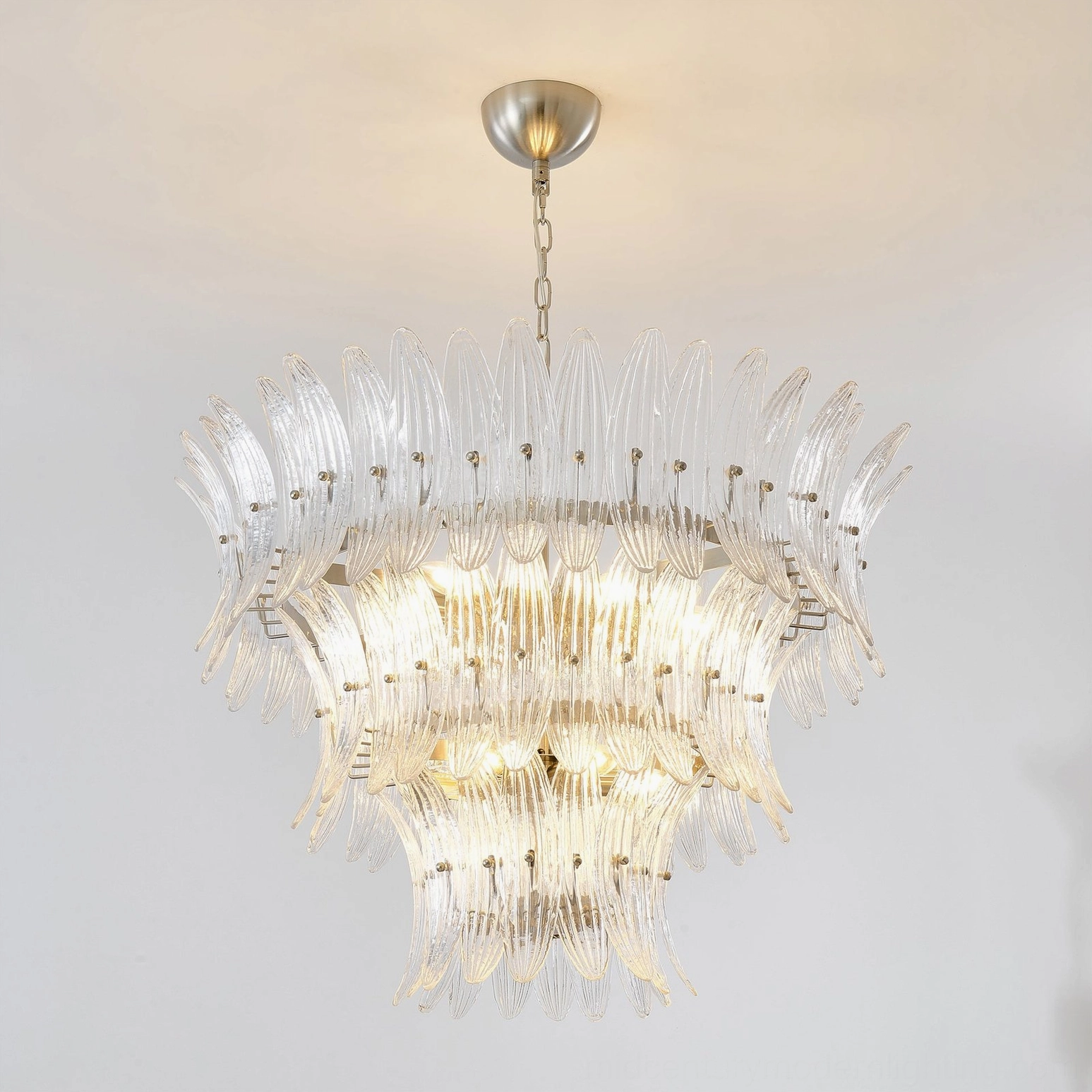 Front three-quarter view of layered glass palm chandelier showing curved glass panels and elegant metal fixtures
