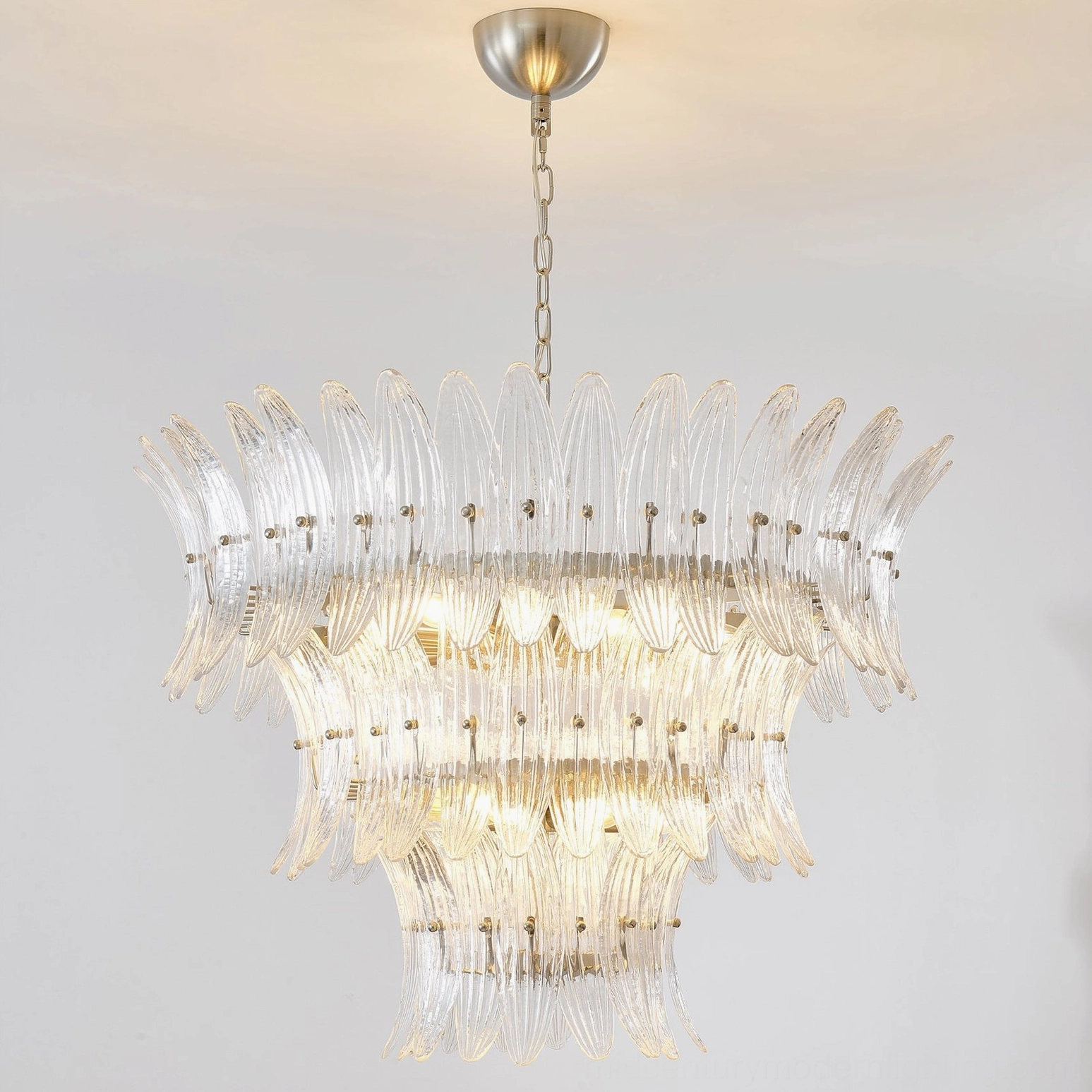 Installation view of layered glass palm chandelier with adjustable hanging chain in contemporary interior