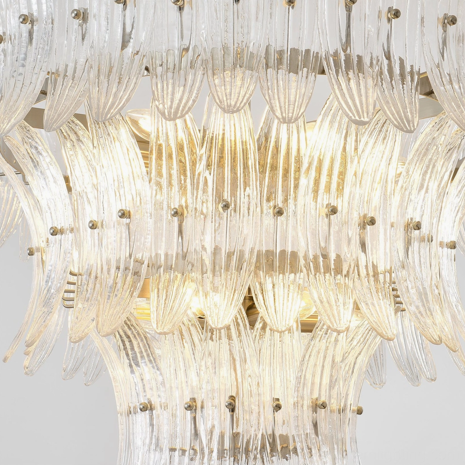 Overhead close-up of glass palm chandelier interior showing layered ribbed glass structure with warm glowing light