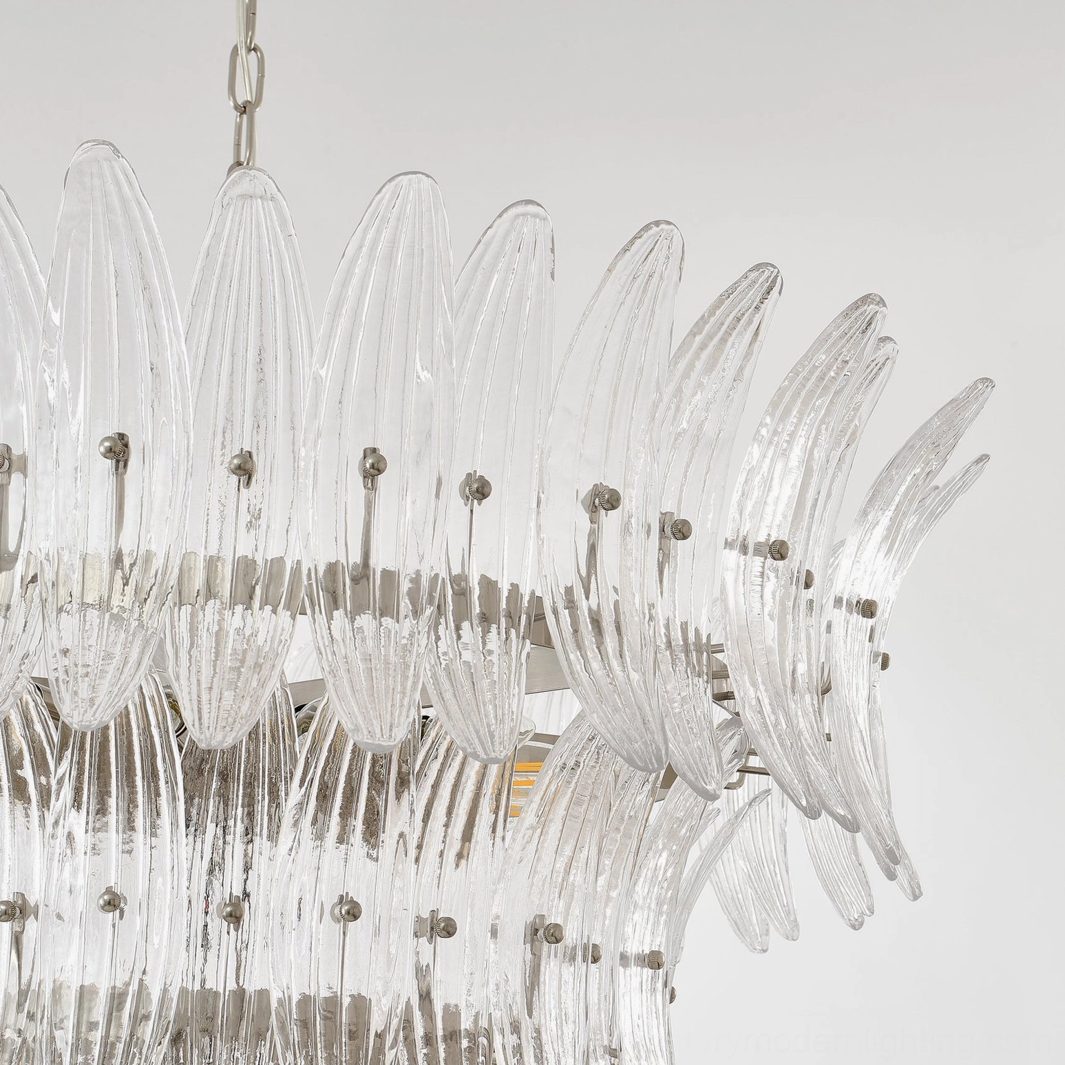 Side view of tiered glass palm chandelier displaying curved clear glass panels and polished metal hardware
