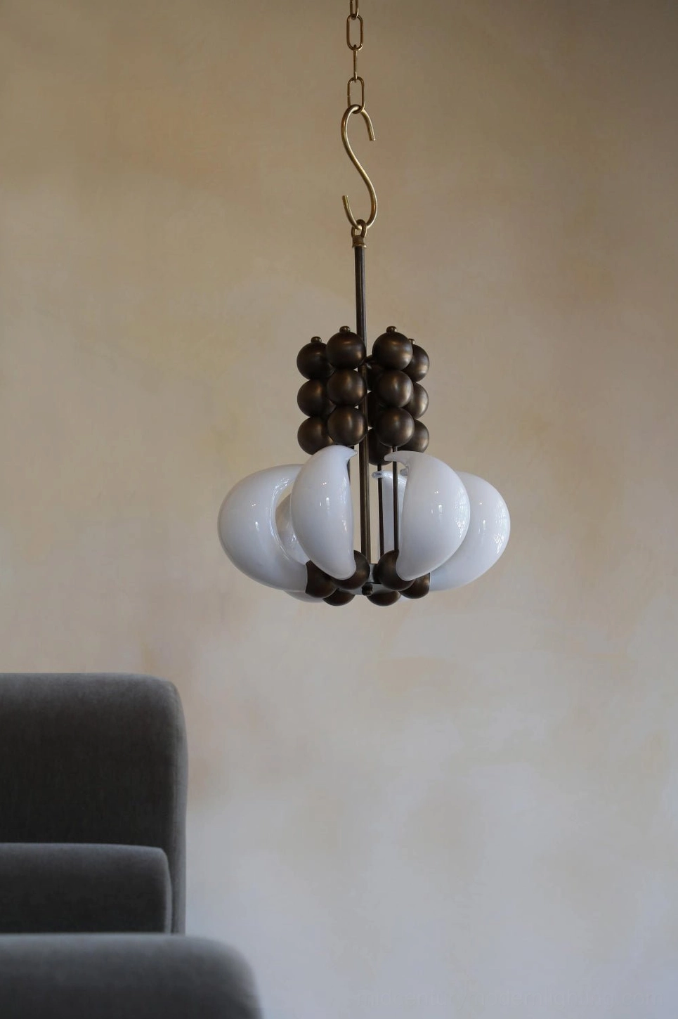 Sculptural glass pendant fixture with dark bronze hardware and curved frosted glass shades - lounge interior setting