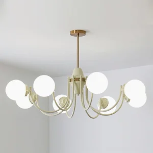 Cream and brass multi-head globe chandelier illuminated, frontal eye-level view in minimalist white room