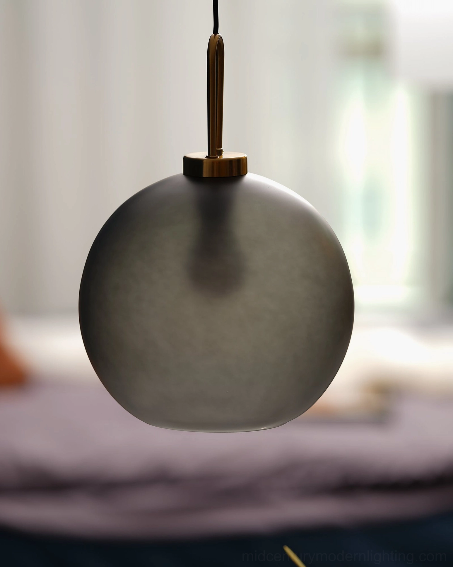 Matte dark gray spherical smoked glass pendant in bedroom side area with soft warm illumination
