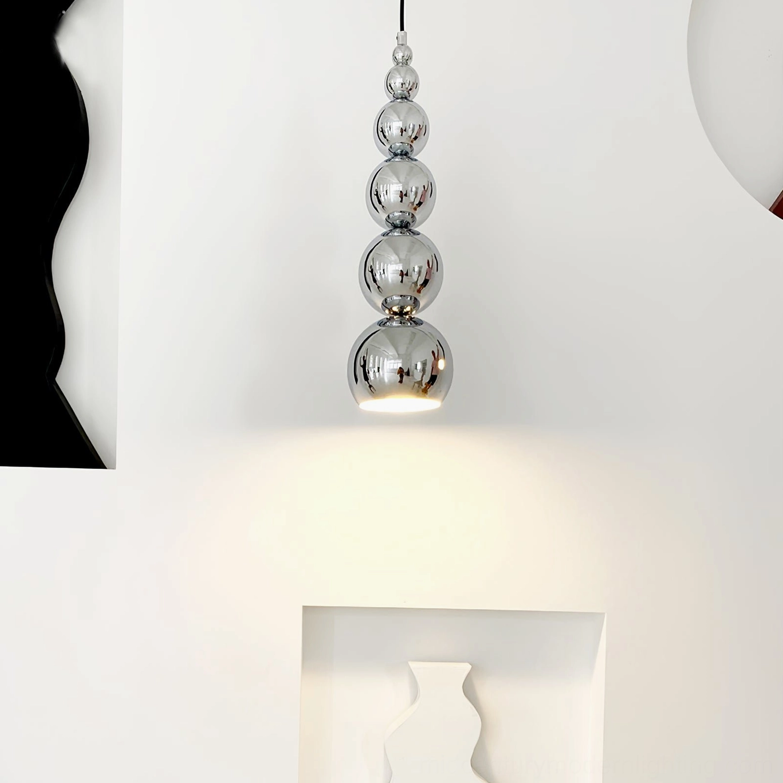 Stacked chrome spherical pendant lamp over recessed display shelves, polished silver finish warm downlight