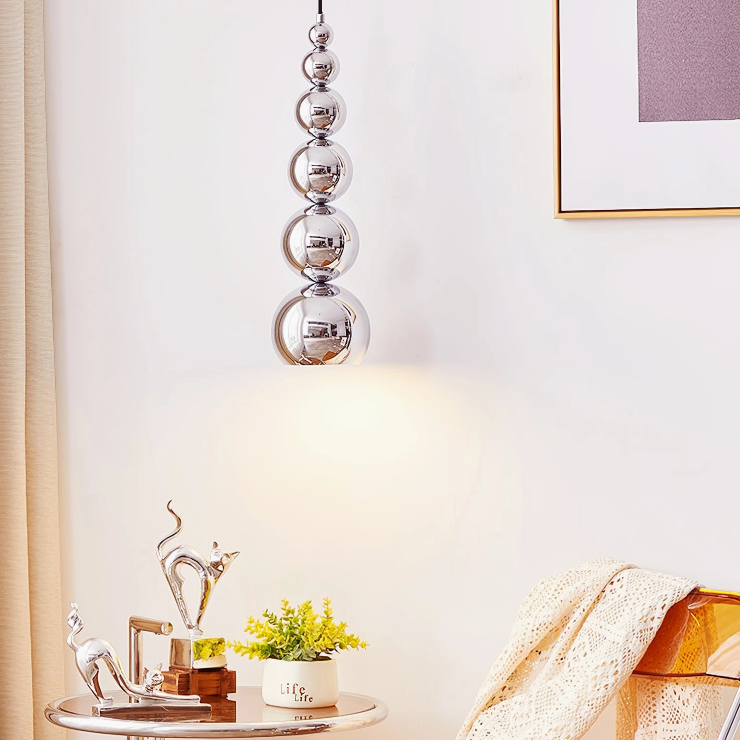 Stacked chrome globe pendant light in modern living area with side table and wall art, warm ambient accent lighting