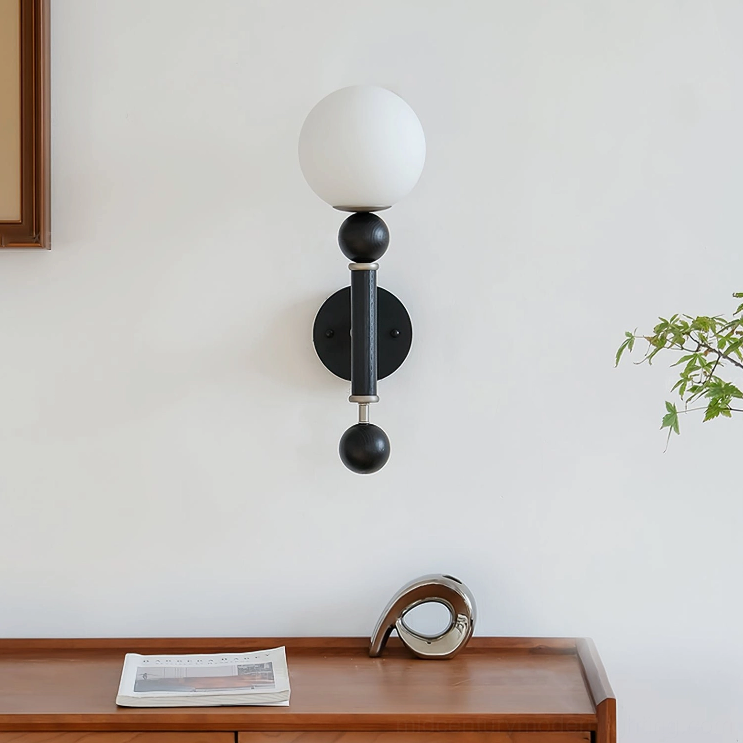 Unlit sculptural globe wall sconce on console table with monochrome decor, overhead front angle view