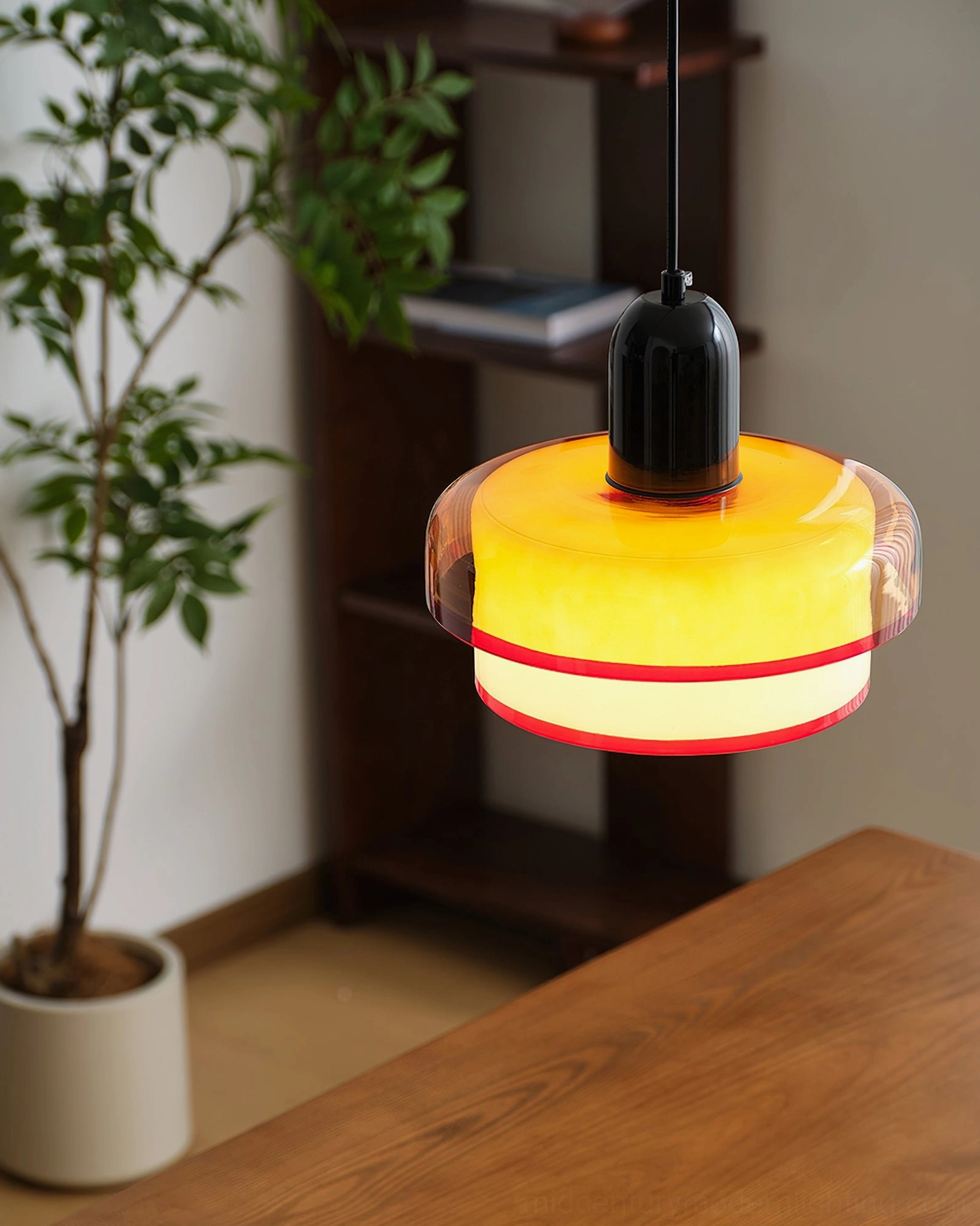 Illuminated pendant light with warm yellow glow showing layered orange and white glass shade