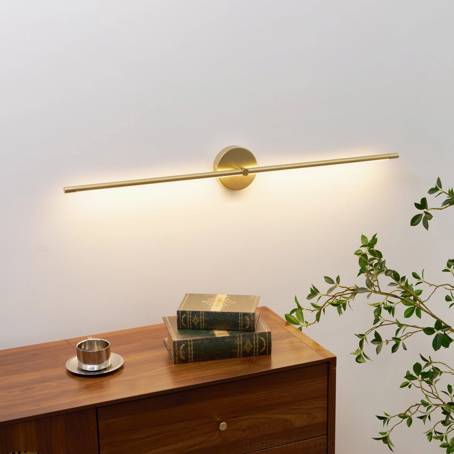 Modern gold linear wall lamp illuminating mid-century interior with wooden table and books