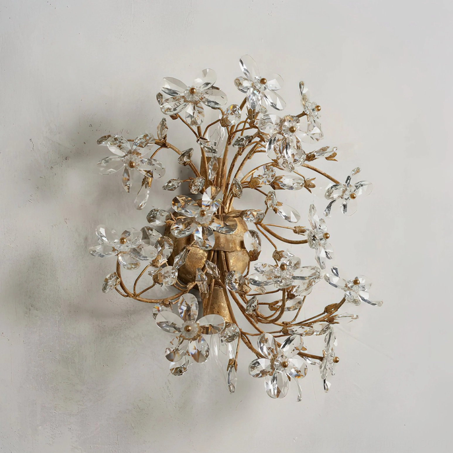 Warm gold metal framed crystal flower wall sconce, eye-level view demonstrating intricate clustered crystal botanical arrangement