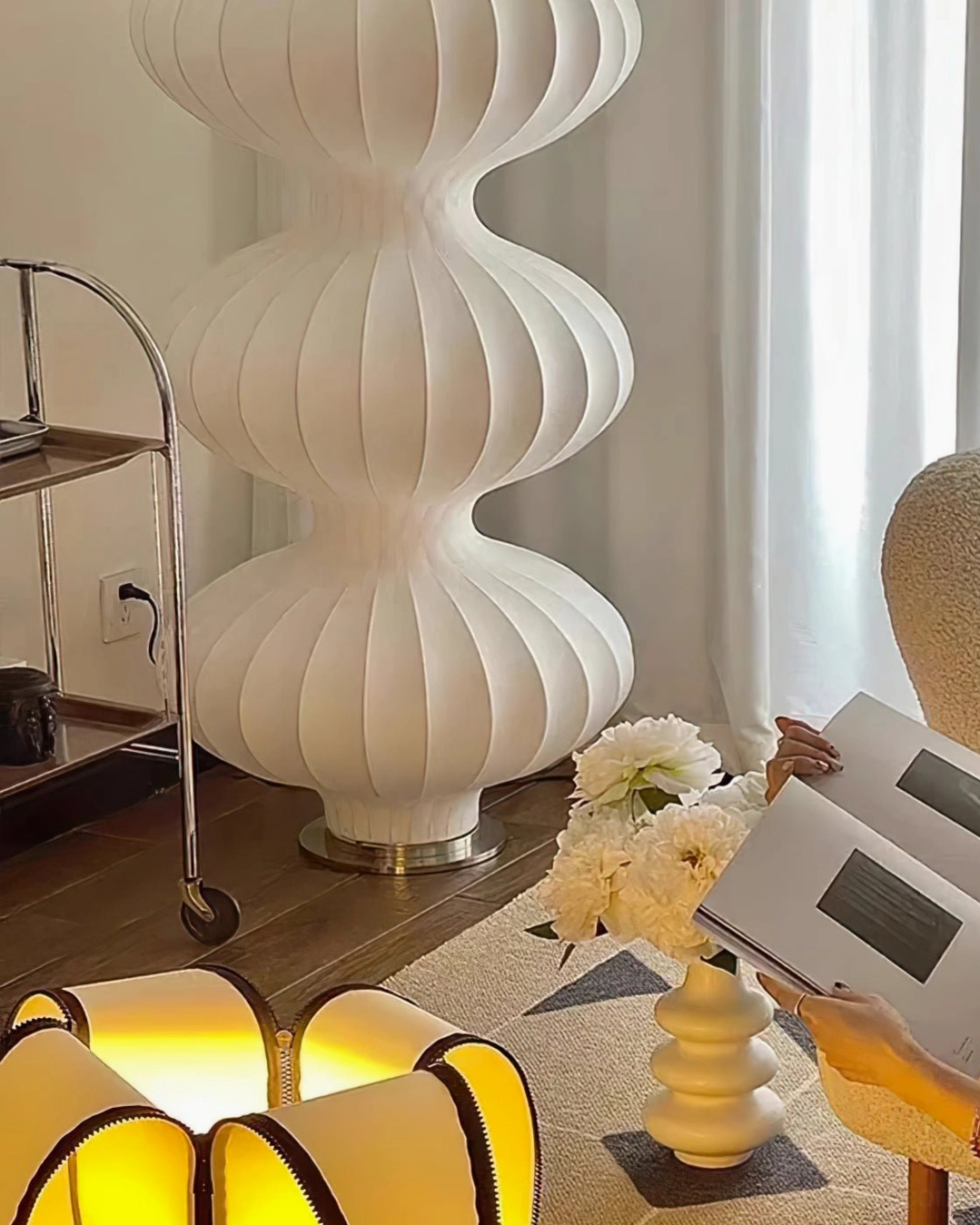 Triple stacked silk gourd floor lamp with person reading, warm home ambiance in bright living room