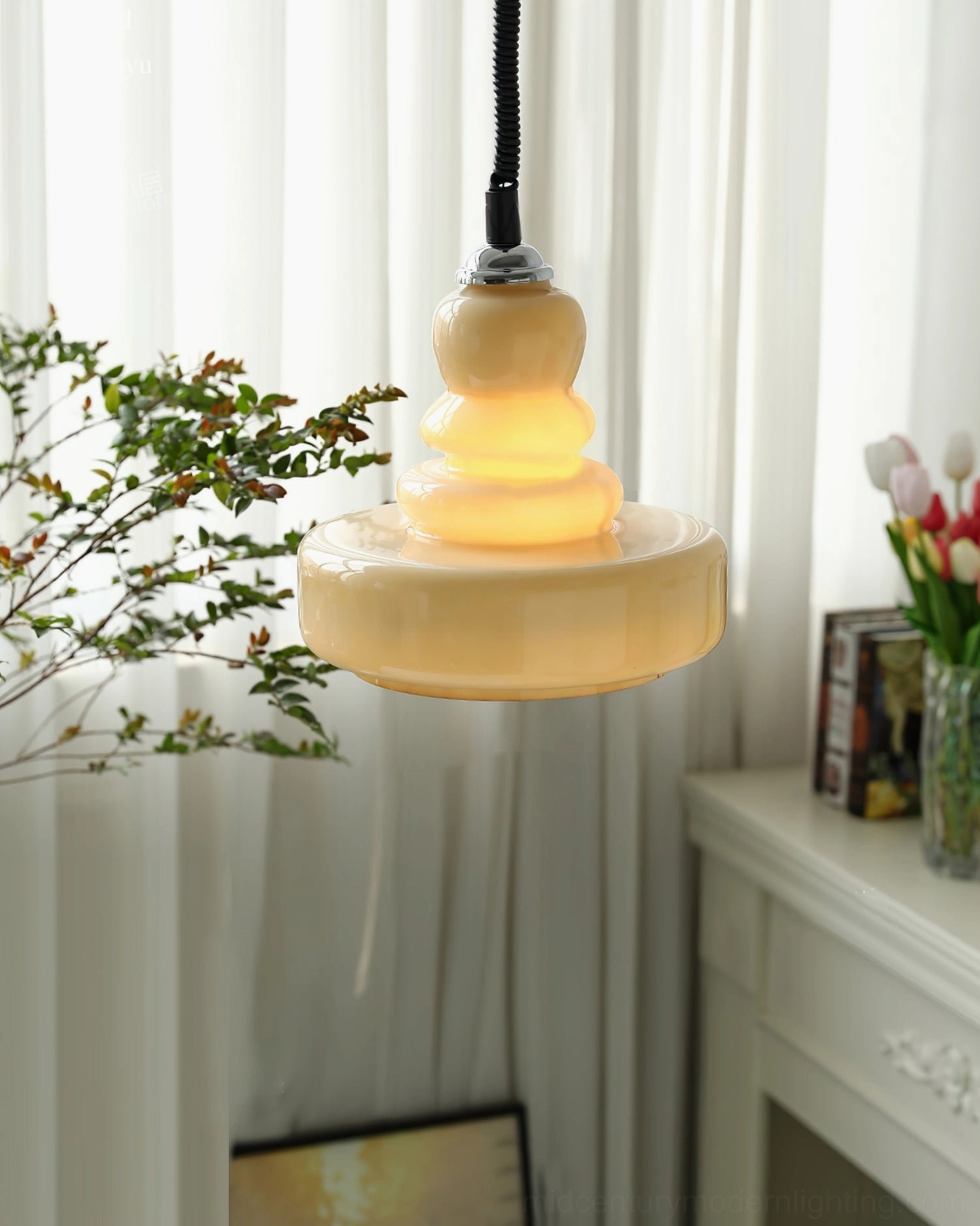 Cream gourd pendant light with stacked glass shade glowing warmly against white mantel and floral decorations