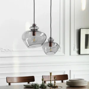 Pair of Grace glass pendant lamps in modern formal dining room with smoked glass shades and ornate white trim