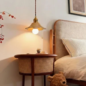 Vintage ceramic pendant light with brass-ceramic design hanging in warm bedroom interior with wicker nightstand