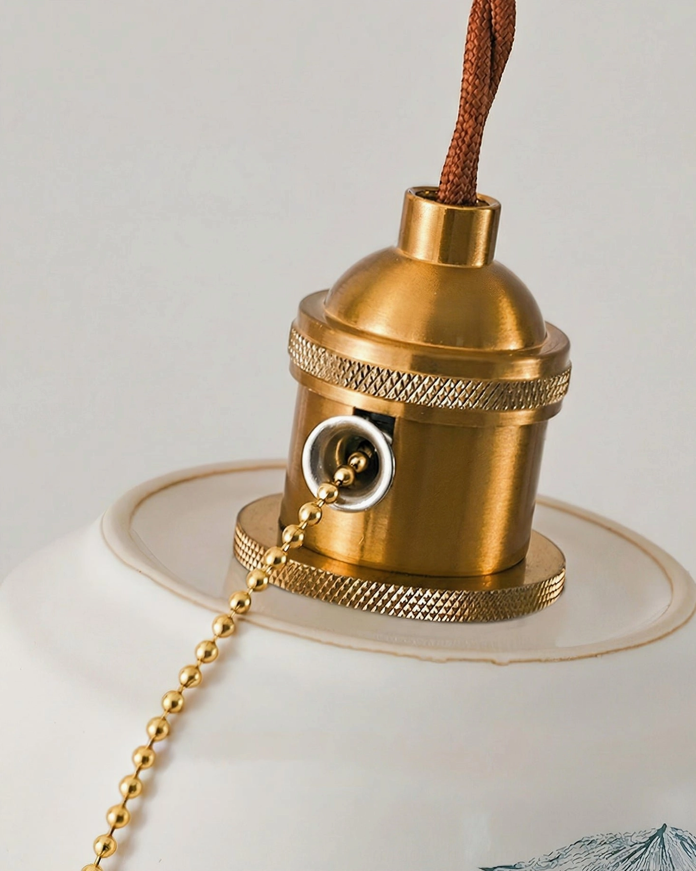 Side close-up of Grange pendant light featuring knurled brass fixture and braided suspension cord