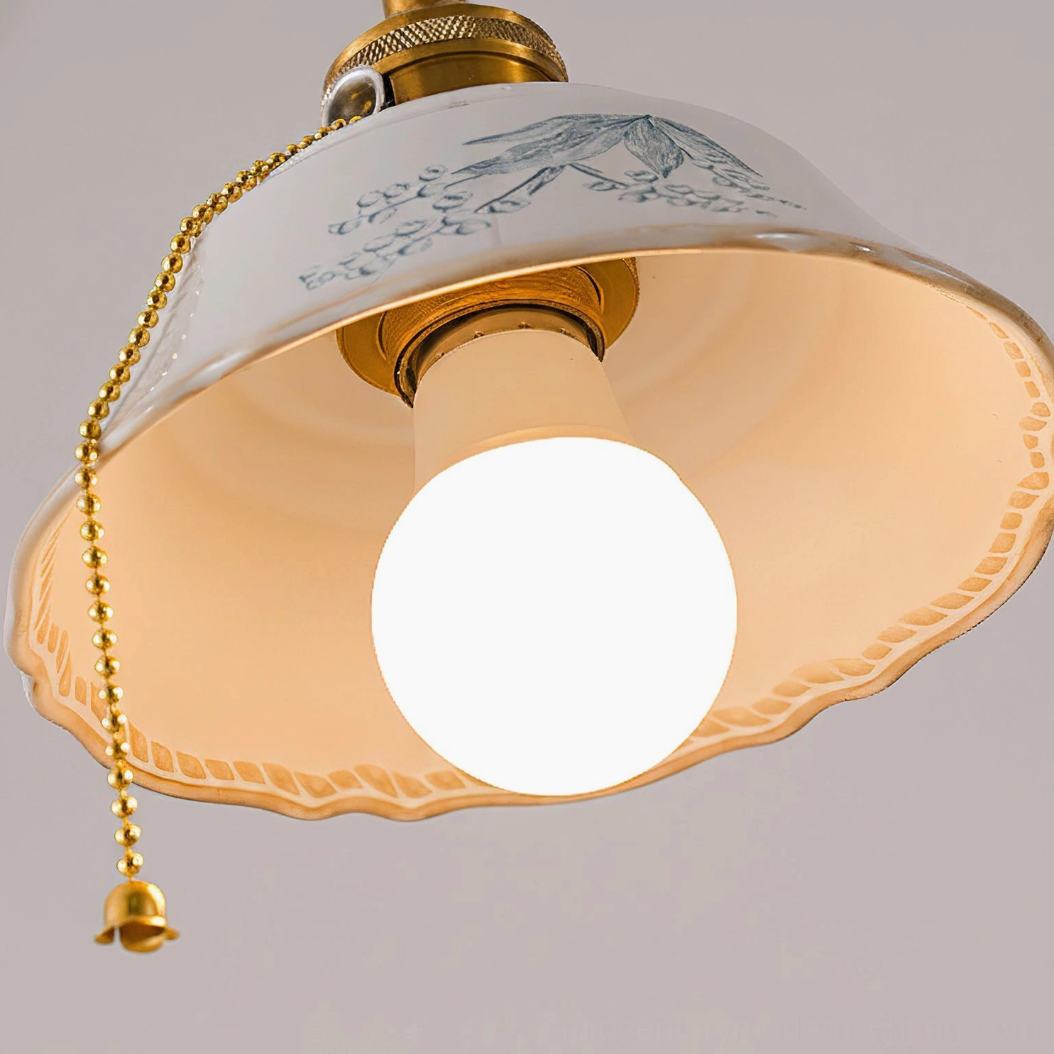 Bottom view of ceramic pendant light interior showing scalloped shade, exposed bulb and pull chain