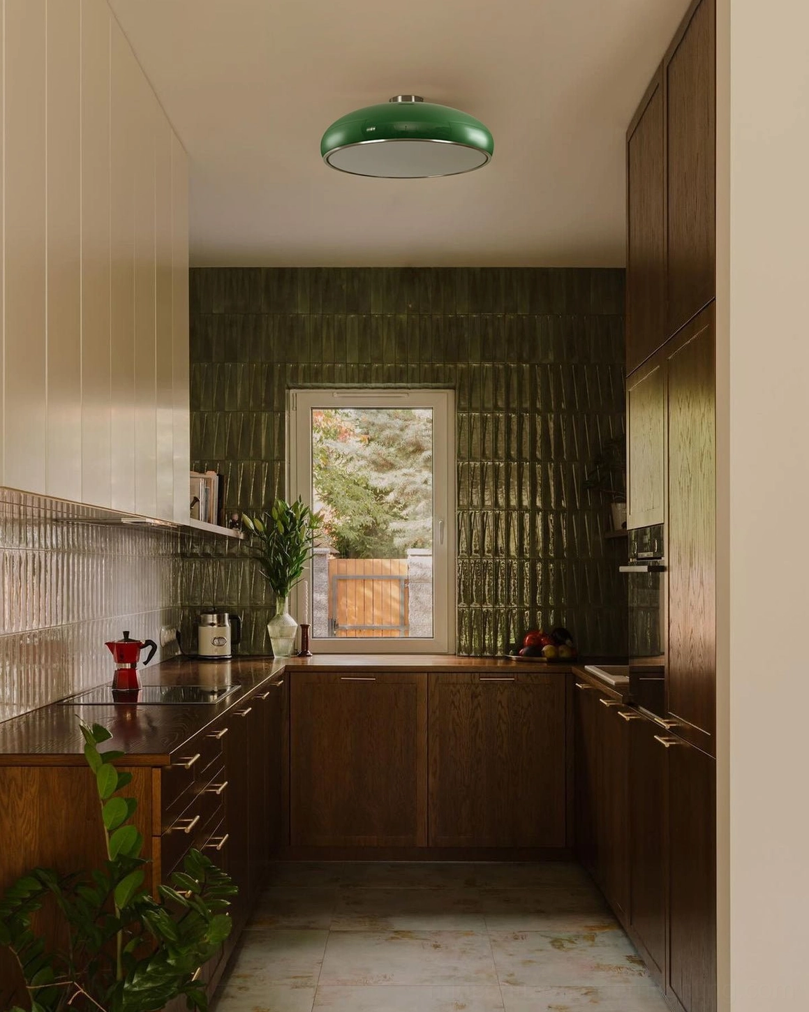 Green semi-flush ceiling light in retro kitchen with dark green tile backsplash and warm wooden cabinet cabinetry