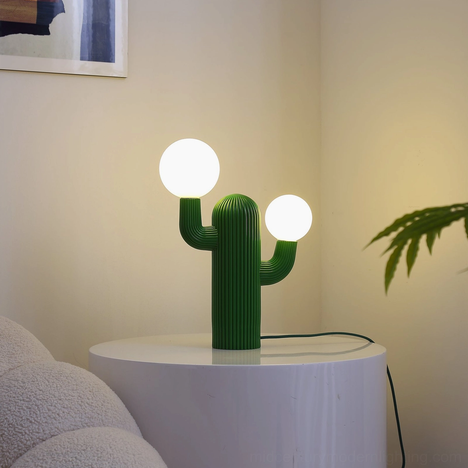 Green cactus table lamp with illuminated warm bulbs in living room setting, botanical wall decor backdrop