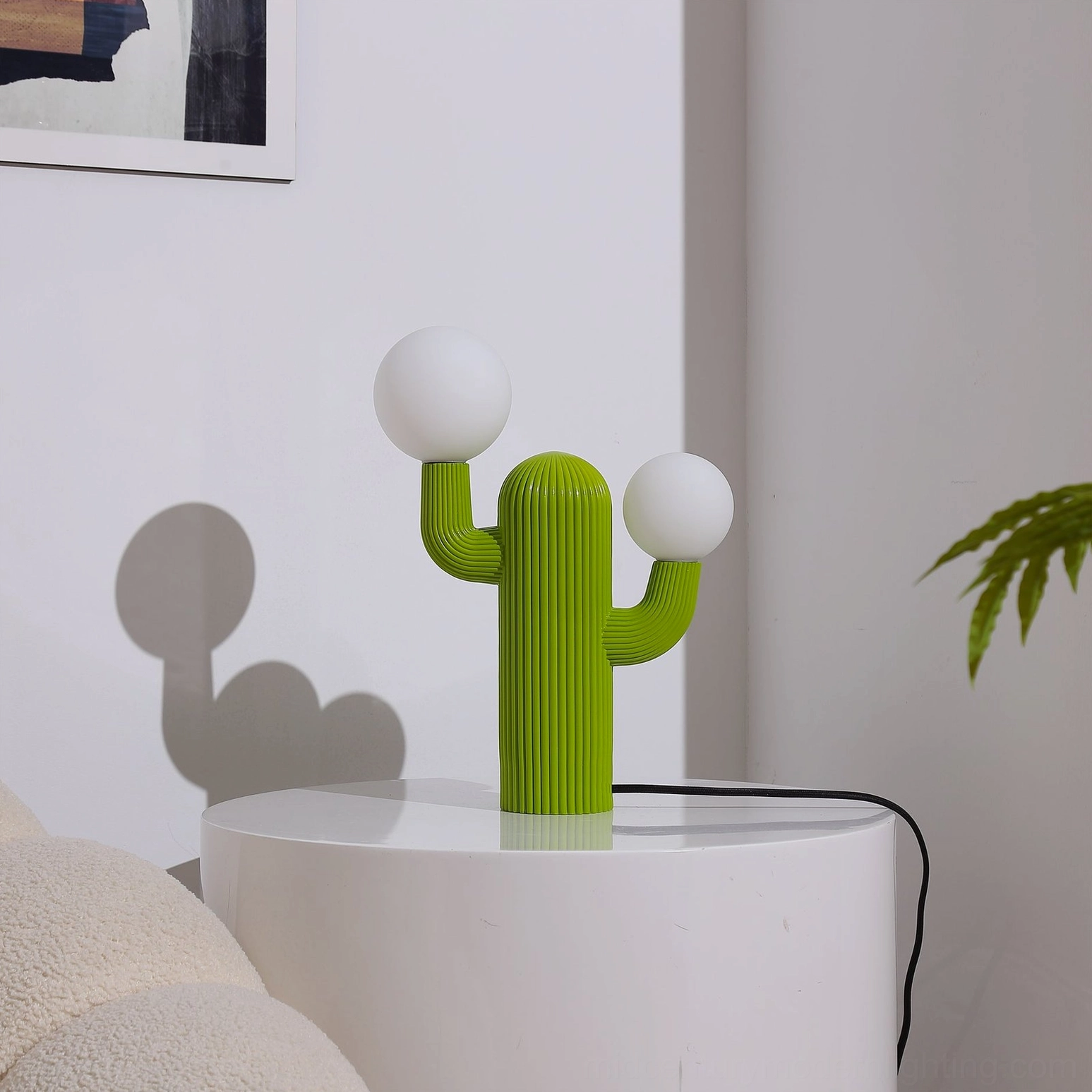 Green sculptural cactus table lamp with unlit white bulbs, minimalist indoor display with soft wall shadows