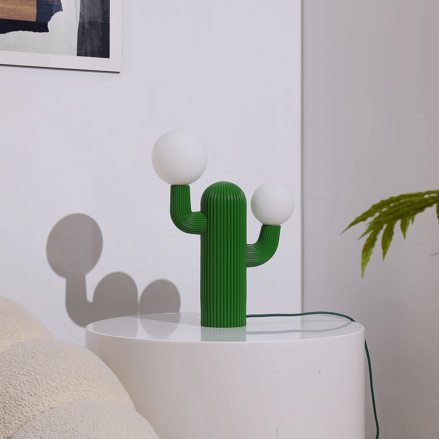Green ribbed cactus table lamp with spherical bulbs, front three-quarter view on minimalist backdrop
