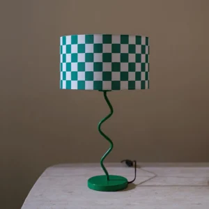 Modern chessboard pattern table lamp with matte green base on wooden table with cord details