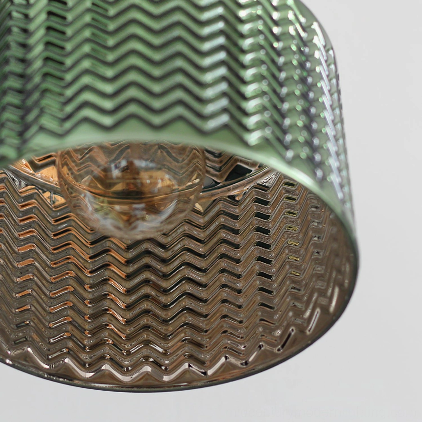 Close-up detail of chevron embossed green glass shade with visible interior bulb and texture