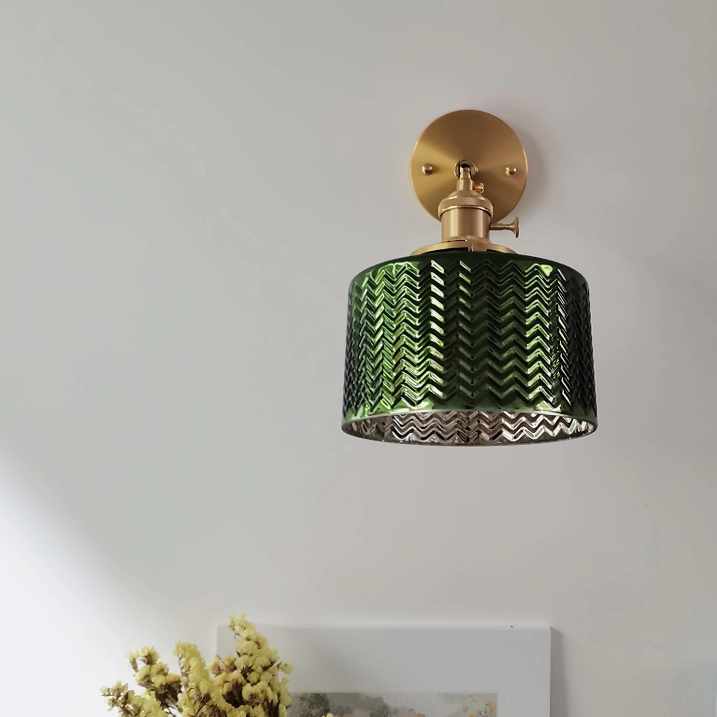 Green glass wall sconce architectural detail showing brass fixtures and glass shade connection