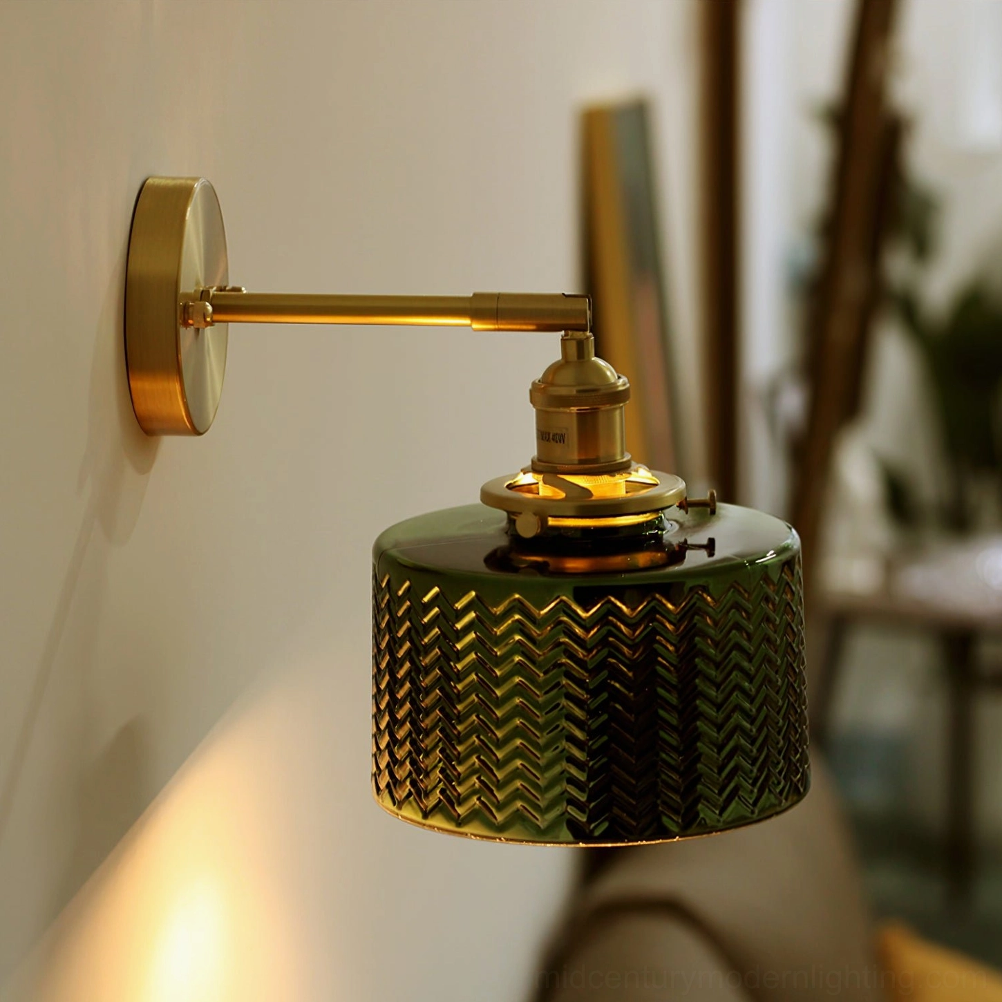 Vintage green glass wall sconce in minimalist interior setting with botanical accents