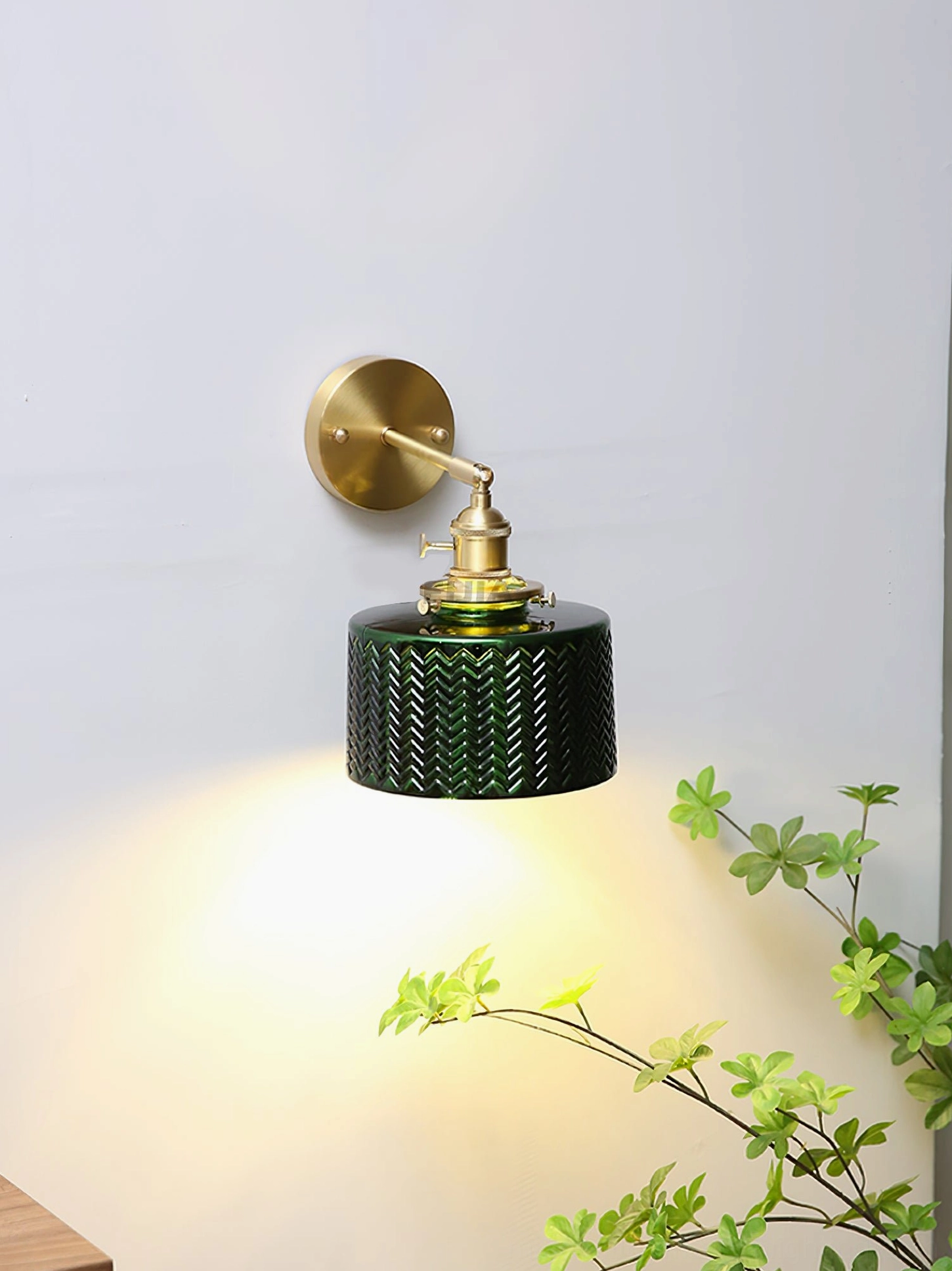Side profile of vintage green glass wall lamp with warm downlight cast on wall