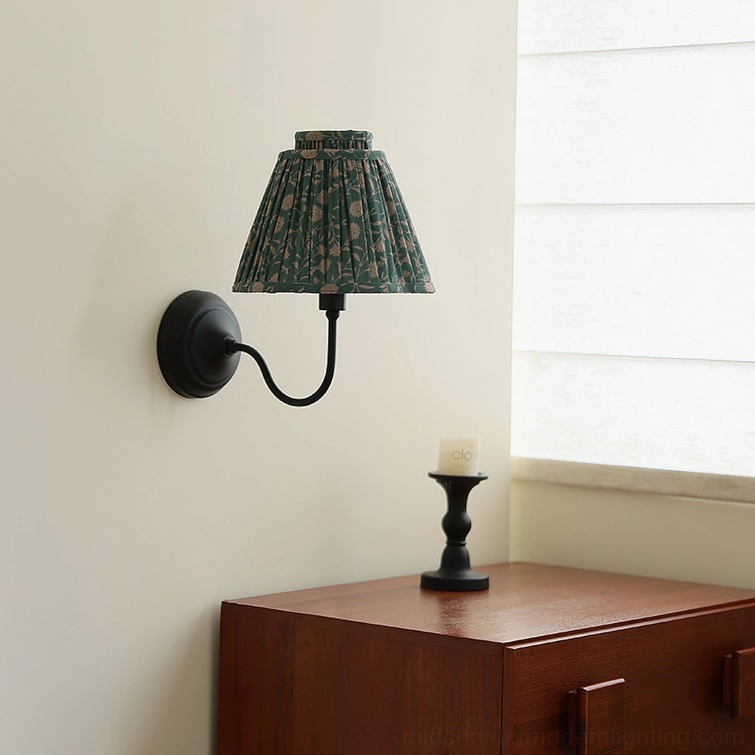 Green floral pleated wall sconce positioned above wooden bedside nightstand, bedroom decor