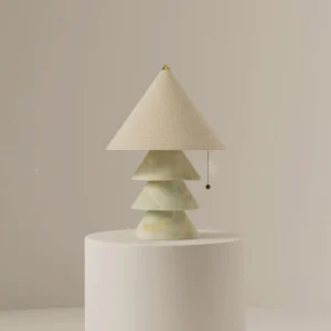 Light green jade marble pyramid table lamp displayed on pedestal with warm neutral backdrop