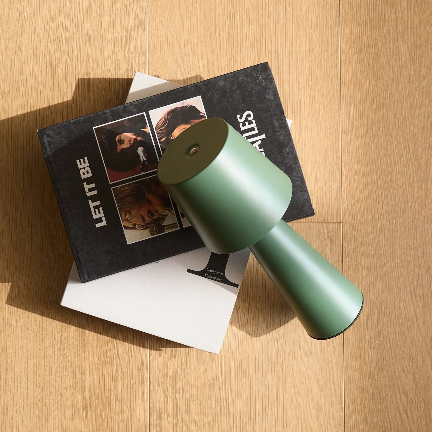 Sage green rechargeable lamp three-quarter flat lay view with Beatles books on wooden surface