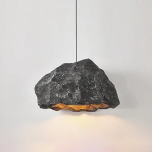 Charcoal grey Kusa pendant lamp with natural rough stone surface and warm ambient glow – three-quarter view showing sculptural organic form
