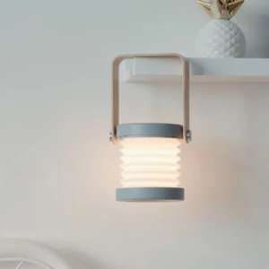 Grey and wood lantern table lamp displayed on home shelf in minimalist interior, creating soft ambient lighting in scandinavian living room