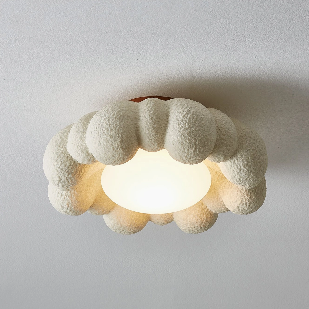 Gross ceiling light fixture with sculpted cloud form, warm LED glow illuminating organic resin surface design