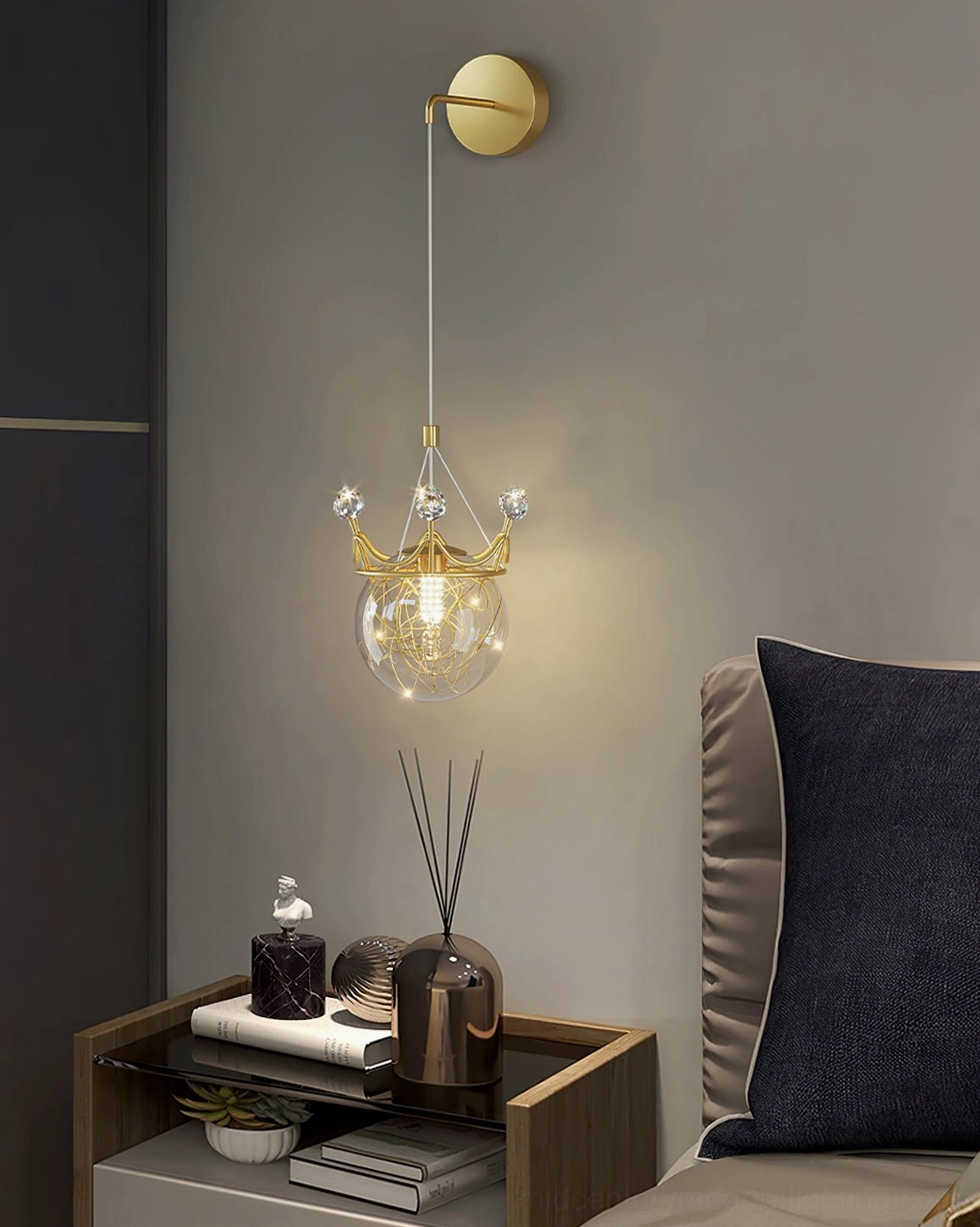 Crown wall light fixture installed above bedroom nightstand with warm glowing hand-blown glass