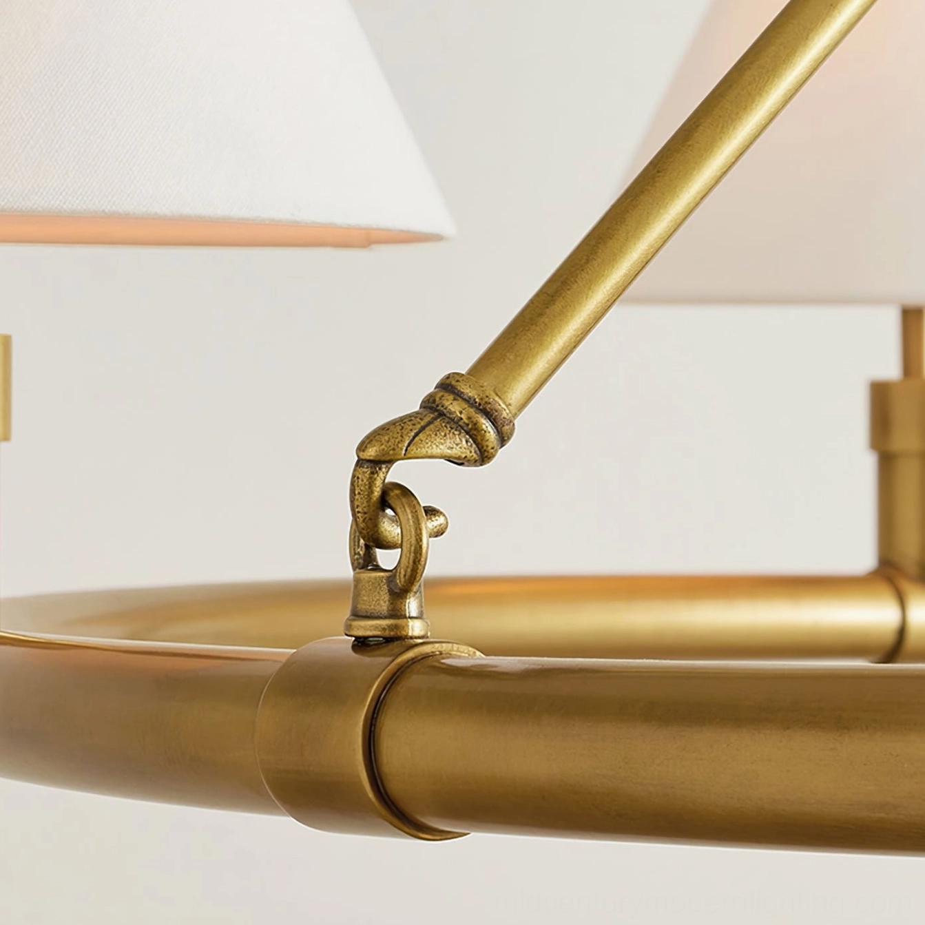 Close-up detail of brass chandelier hardware showing knotted gold metal joint and white fabric shade edge