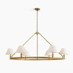 Hackney six-arm brass chandelier front view with white fabric shades and warm gold frame, studio lighting