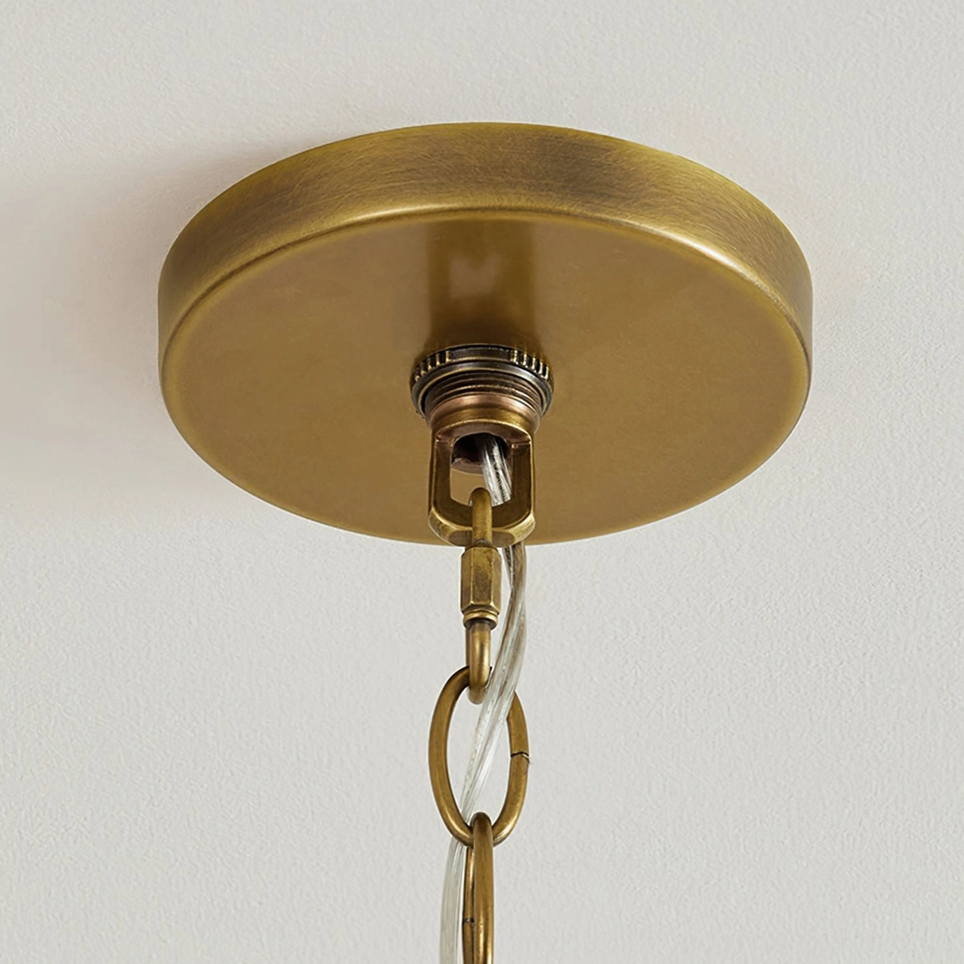 Polished gold ceiling mount fixture of Hackney chandelier showing hanging chain and suspension ring