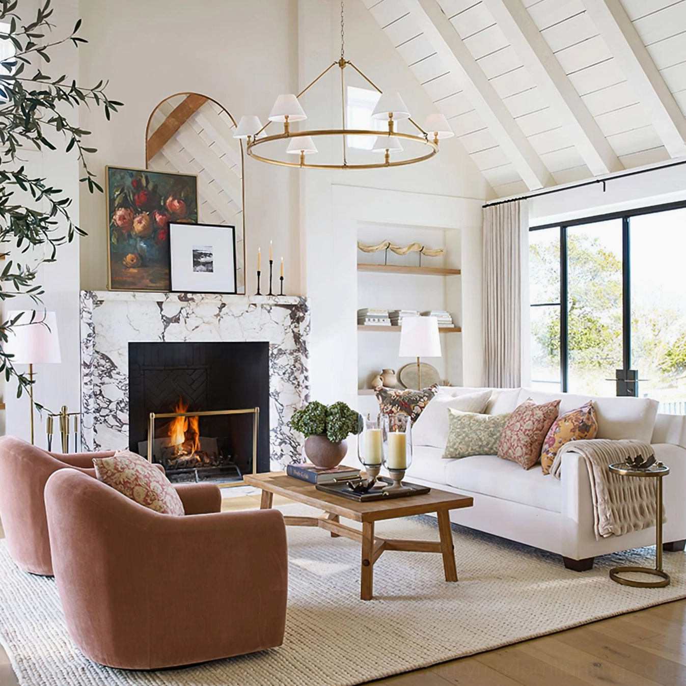 Brass six-arm chandelier illuminating farmhouse living room with vaulted ceiling and marble fireplace