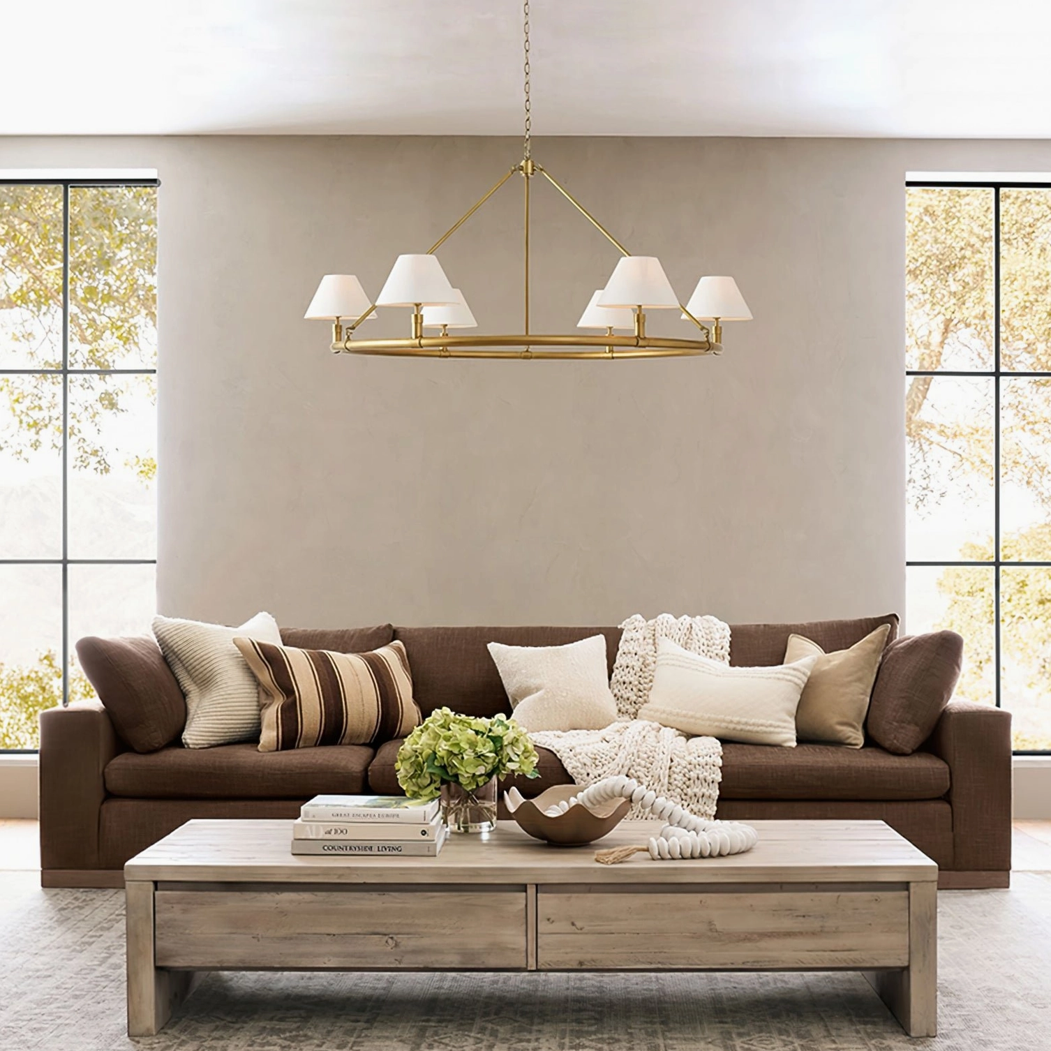 Overhead view of Hackney chandelier in modern living room with brown sofa, warm metal frame
