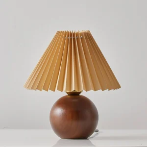 Haddie table lamp unlit on tabletop, showing khaki pleated fabric shade construction and wooden base details