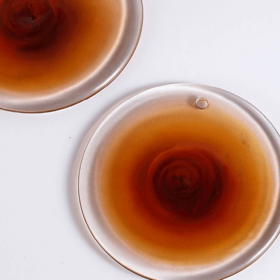 Individual hand-blown amber gradient glass discs displaying artisanal variation and flat-lay detail