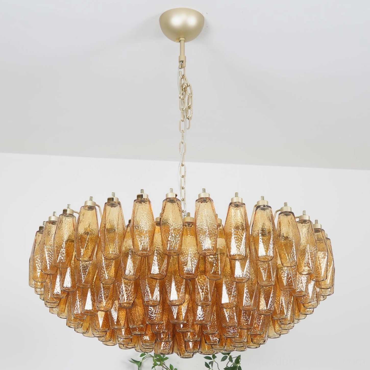 Close-up detailed view of hand-blown amber glass rhombi droplets in Murano chandelier against white studio background