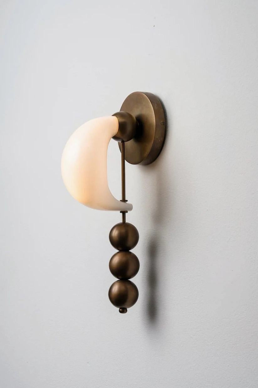 Hand-formed bent glass wall sconce showing artisanal craftsmanship, sculptural metal base and organic curved glass composition