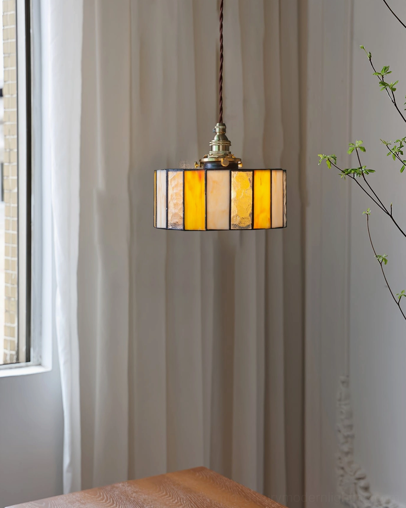 Warm amber stained glass pendant lamp with bronze brass fixture showcasing handcrafted glass panel artistry