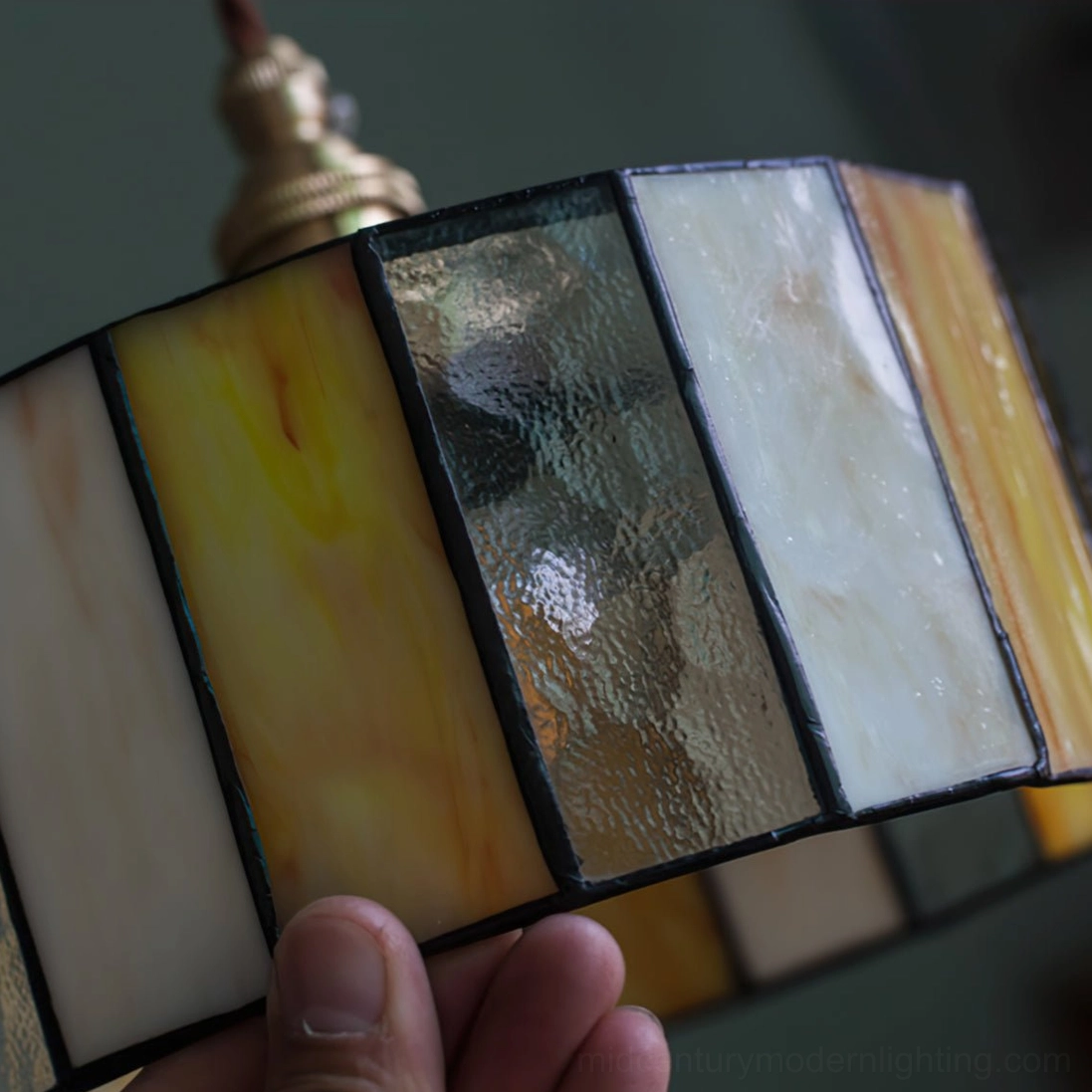 Handcrafted stained glass pendant lamp featuring warm amber and cream glass panels with bronze brass fixture detail