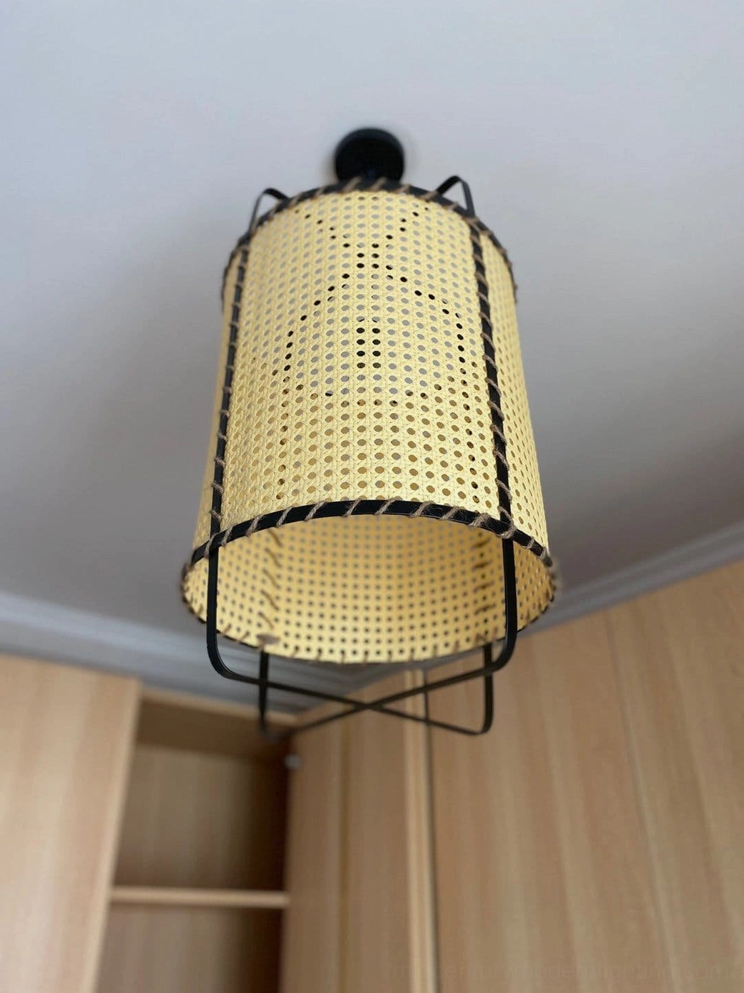 Handwoven rattan cane pendant lighting fixture, close-up showing intricate mesh pattern, natural bamboo color, and jute cord hand-stitching technique