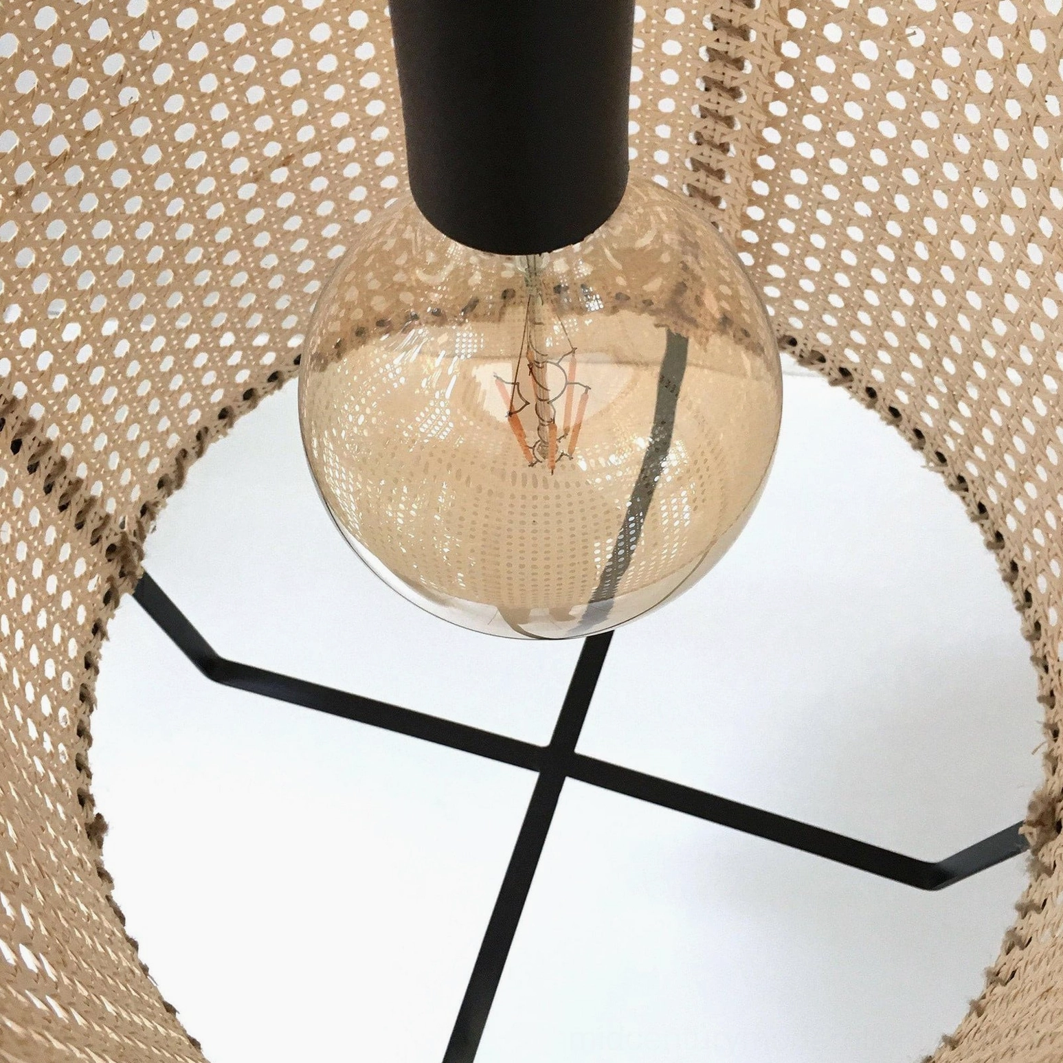 Handwoven rattan cane pendant lighting in bohemian interior, featuring natural material warmth, artistic shadow casting, and contemporary minimalist styling