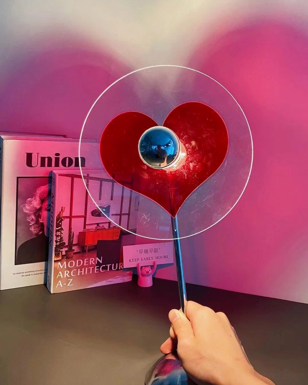 Heart projection lamp casting red ambient glow in modern minimalist bedroom interior